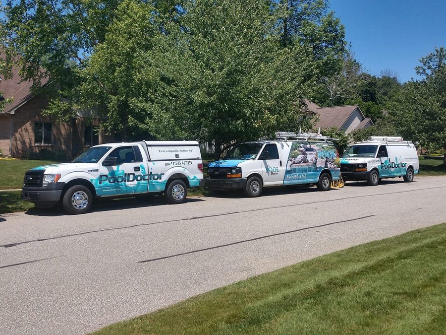 Three Pool-Doctor trucks and vans at a job